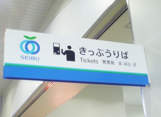 Panneau suspendu dans une gare japonaise, avec le mot きっぷ écrit en hiragana au-dessus du mot « Tickets »