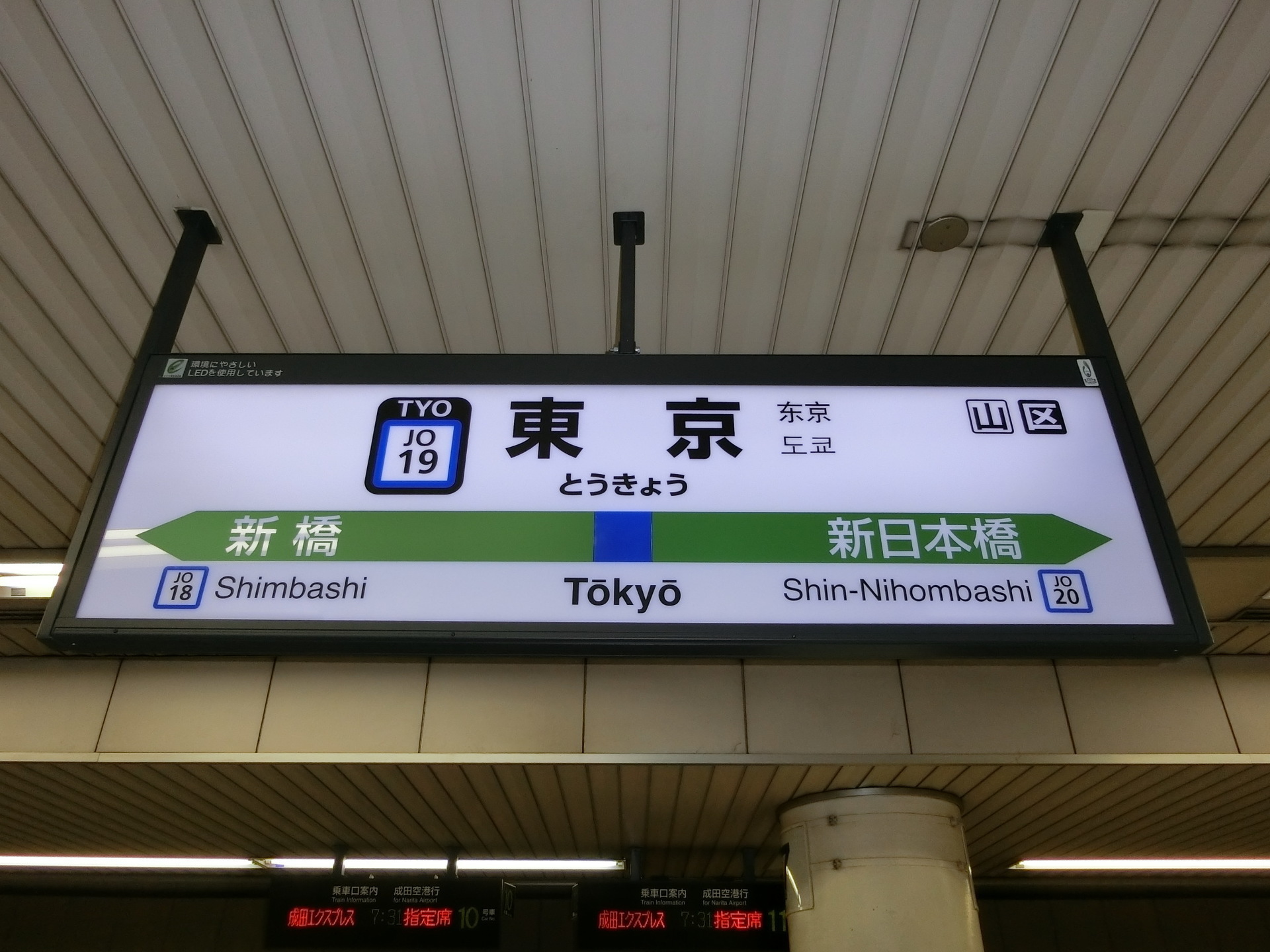 Le panneau de la gare de Tokyo, avec le nom de la ville écrit en hiragana sous les grands caractères : とうきょう, dont le ょ est plus petit que les autres signes