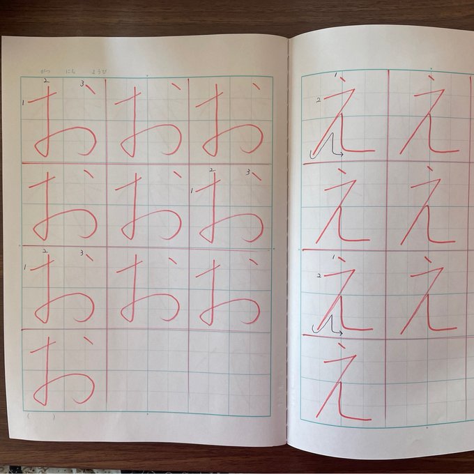 Un cahier d'écriture japonais ouvert sur お et え, avec les modèles tracés en rouge et le numéro de chaque trait